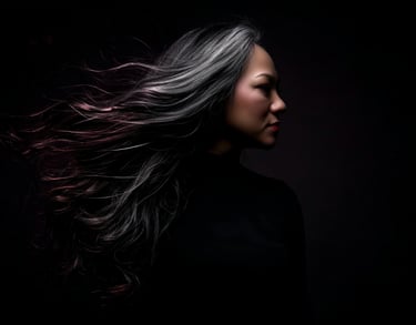 A dramatic lit portrait of Elda Orozco against a stark, pitch-black background, matching the site's magical realism style