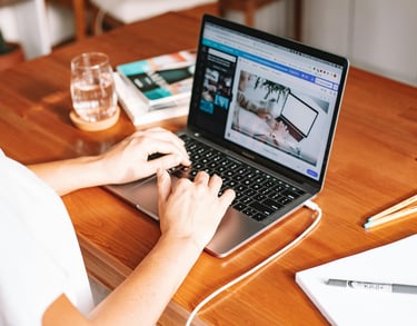 a woman sitting at a table with a laptop and a glass of wine