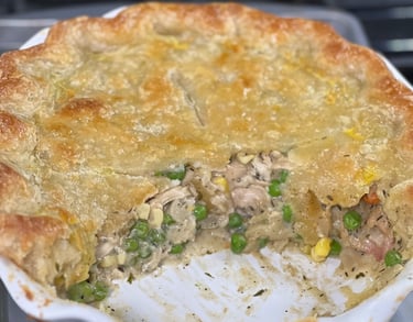 A golden brown homemade chicken pot pie with a flaky crust, filled with peas, corn, and creamy gravy.