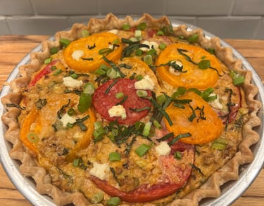 Freshly baked savory tomato pie with yellow and red tomato slices, basil, and scallions in a flaky crust.