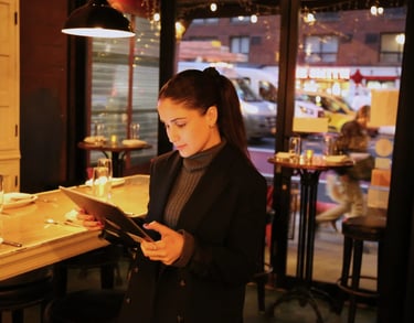 Young woman looking at a tablet, with a restaurant interior visible in the background