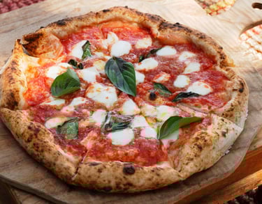 eine neapolitanische Pizza mit Mozarella und Basilikum auf einem Holzbrett