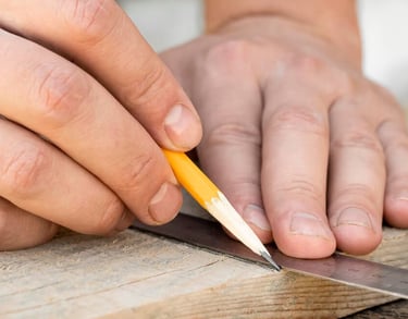 gros plan main traçant une planche de bois