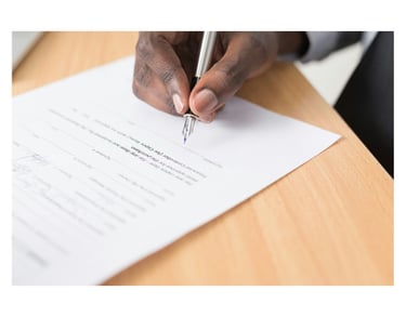 A man's hand holding a fountain pen over an employment contract