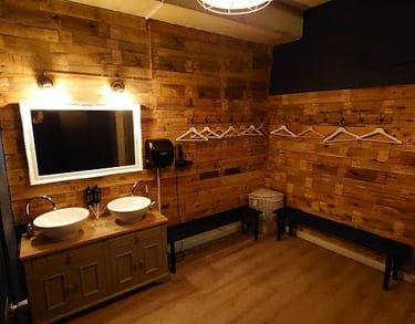A male changing room from a private gym facility in east London. There is a sink, mirror and benches