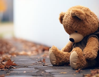 a teddy bear sitting on the ground next to a wall