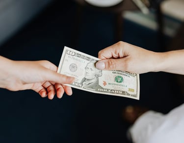two people holding onto a dollar bill representing gold ira fees and a guide to understanding gold ira fees