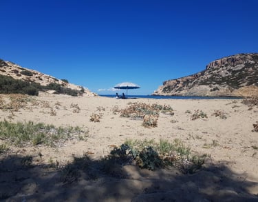 A couple under an umbrella on a beach in Antiparos island