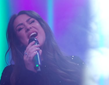 a woman in a black dress singing into a microphone
