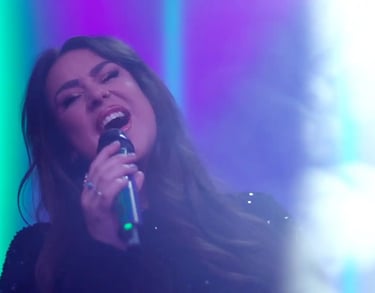 a woman in a black dress singing into a microphone