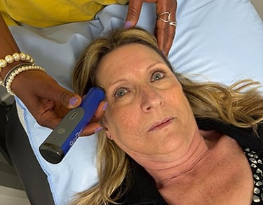 older woman laying on a doctors table receiving microneedling treatment