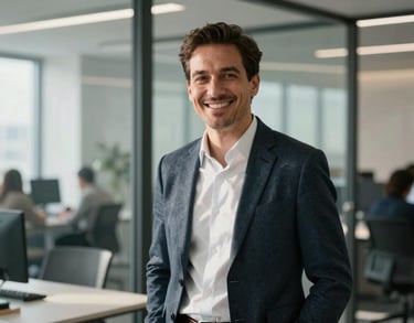 A portrait of a male strategist in professional business-casual clothing, smiling warmly inside a sunlit, modern North American workspace with glass partitions.