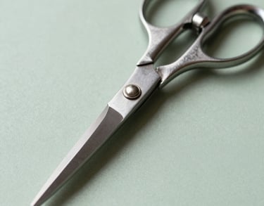 Macro photography of professional tailoring shears on a light green surface, emphasizing the sharp, clean lines and elegant metal design.