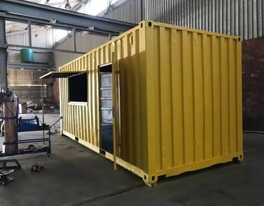Yellow converted shipping container modified with a side window and door for an office or pop-up shop.