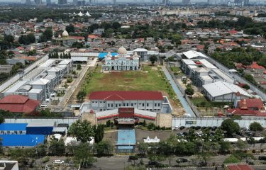 Aerial view of a walled correctional facility complex with a mosque in an urban city landscape.