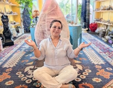 Cricia sits cross-legged in a crystal shop in front of a giant rose quartz flame tower.