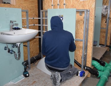 Plombier posant un cadre mural et un lavabo lors d'une rénovation résidentielle à Odza