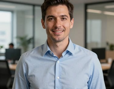 A professional headshot of a man in a business-casual light blue shirt, standing in a contemporary Indiana office suite.