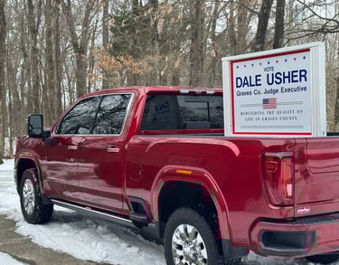 red pick-up truck with a sign in the bed saying vote, dale usher graves co. judge executive