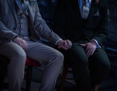 two grooms sitting holding hands