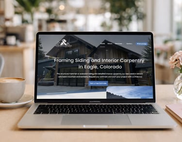 Laptop displaying a framing and siding construction website on a desk with coffee and flowers.