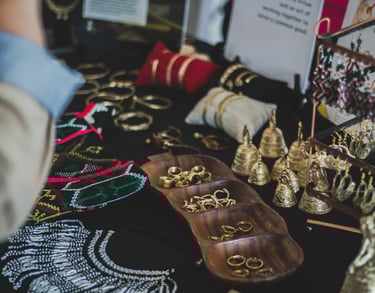 Exhibición de joyas hechas a mano con anillos, brazaletes y aretes étnicos en un mercado.