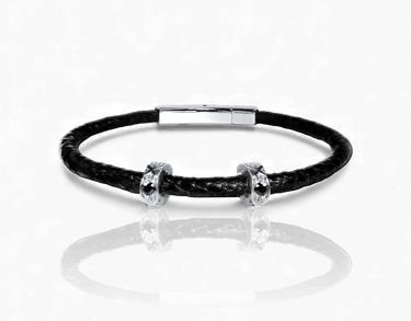 Handcrafted black braided leather men's bracelet with silver skull charms and magnetic clasp.