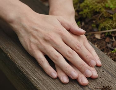 A close-up photography shot of two hands gently resting on a wooden surface, soft natural lighting, earthy soil brown and moss green colors in the background, North American / Canadian style.