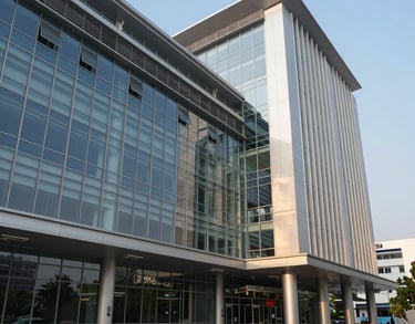 A crisp architectural photograph of a modern pharmaceutical research wing in a South Asian urban setting, featuring glass walls and steel accents under bright afternoon sunlight.