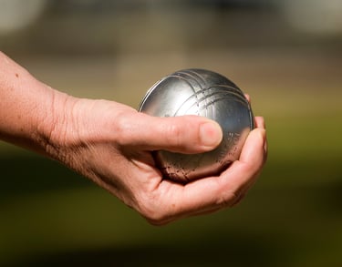 une main tient une boule de pétanque