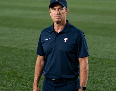 Portrait of a head softball coach in North American / US, wearing a navy team polo, standing confidently on a lush green field, professional lighting.