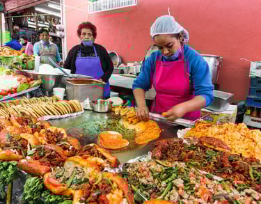 Street food vendors preparing authentic pambazos and tacos on a large griddle at a Mexican market.
