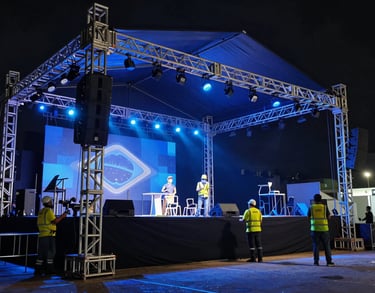 Cinematic shot of a stage being set up for a major event in Brazil, workers positioning steel structures under dramatic blue lighting.