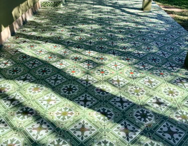 Outdoor patio featuring green patterned cement tiles with a vintage floral design in a sunny backyard.