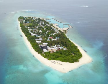 Aerial view of a tropical Maldives island with white sand beaches and turquoise coral reefs.