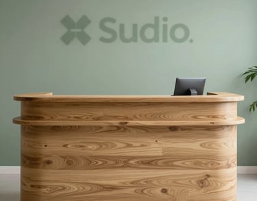 Reception desk of a dental clinic made of natural light oak wood, behind it a wall in sage green with the studio's subtle branding.