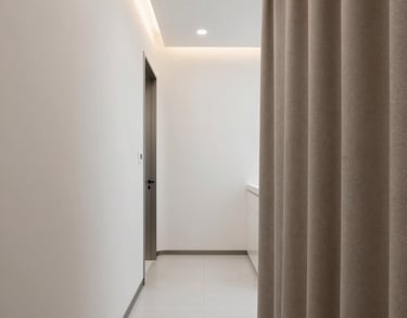 Detail of the dental clinic interior, white walls, soft textiles in taupe color, and a minimalist hallway with warm lighting.