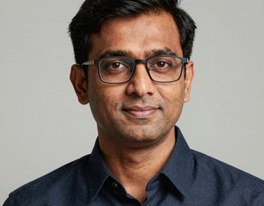 Professional studio portrait of a South Asian / Indian man with glasses, looking professional and trustworthy.