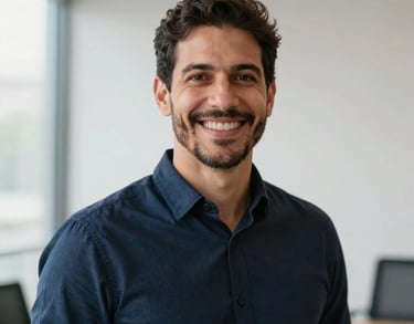 Professional portrait of a male Brazilian leadership coach with a warm smile, wearing a dark navy blue shirt, soft natural lighting in a modern professional setting, crisp white background elements.