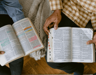 two people sitting on a couch and one is holding a bible