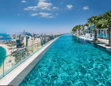 Rooftop infinity pool with clear turquoise water and pale mosaic tiles stretching toward the skyline