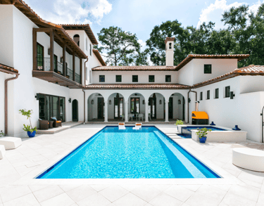 Rectangular courtyard pool with clear blue water and light stone tiling, featuring built-in loungers