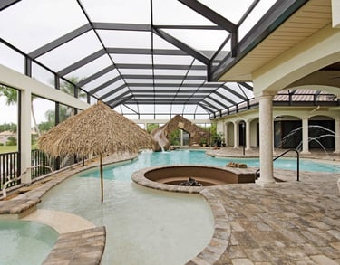 Tropical lagoon pool with light aqua water, tan stone tiling, rock slide and curved spa set under an