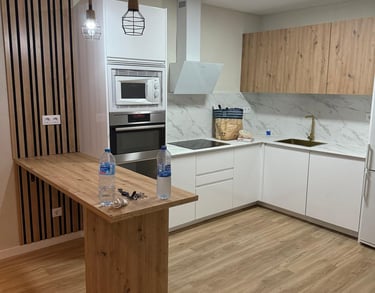 Cocina moderna con barra, muebles de madera y electrodomésticos.