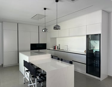 Cocina moderna blanca con isla y sillas altas.