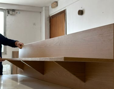 Persona instalando estantería de madera en la pared.