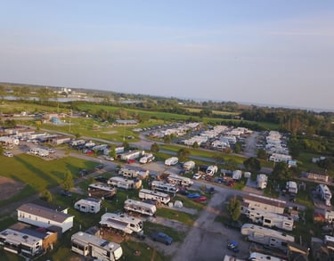 Aerial view of a lakeside RV park and campground with many campers, trailers, and outdoor recreation areas.