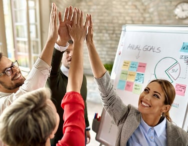Un groupe célèbre une réussite devant un tableau d'objectifs.
