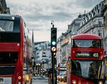 Two red busses at a traffic light