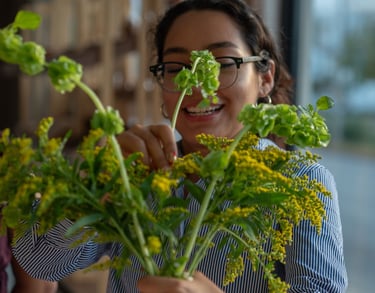 Florista sonriente arreglando un ramo de flores silvestres frescas amarillas y verdes en una tienda.